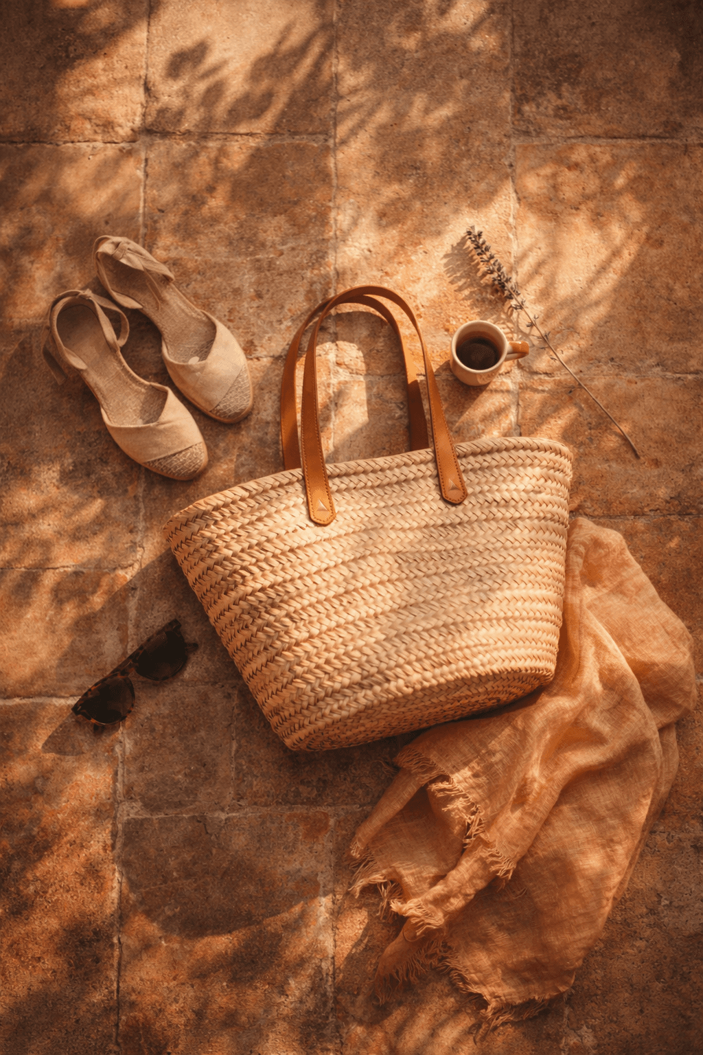 Close-up of raffia bag and espadrille sandals on terracotta tiles