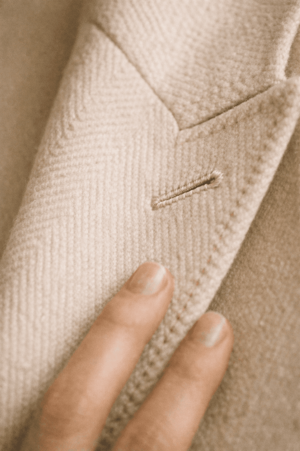 Close-up detail of hand-finished stitching on a cream wool coat